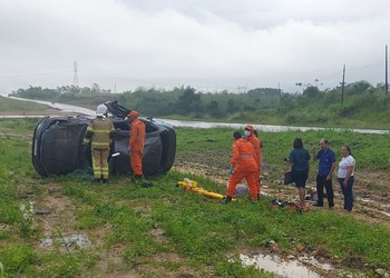Veículo capota com três pessoas e uma fica presa às ferragens na BR 101